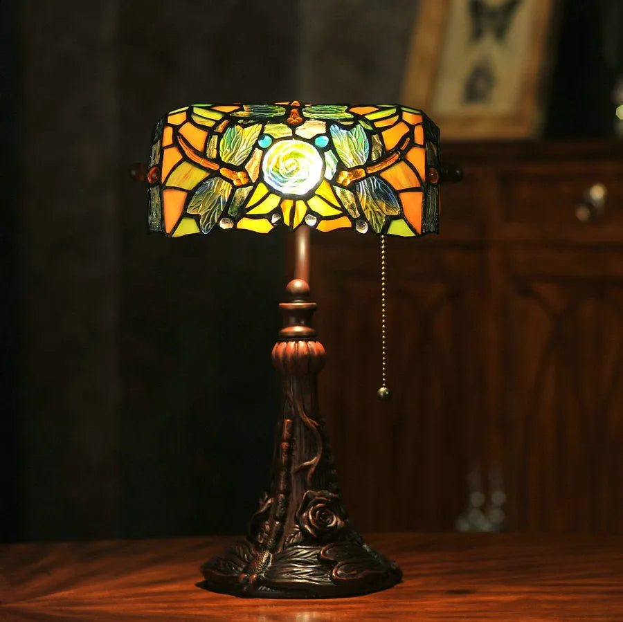 Tiffany-style table lamp with colourful stained glass shade and resin base on a desk