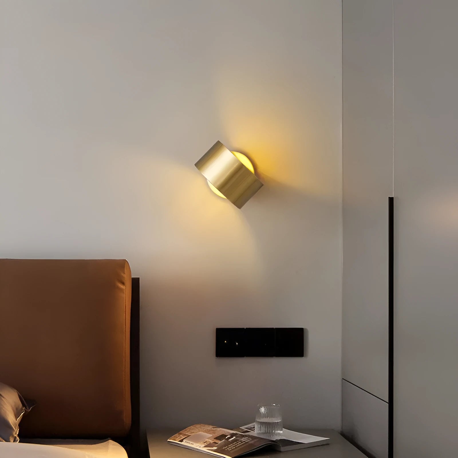 A modern simplistic copper wall lamp shown in a living room setting.