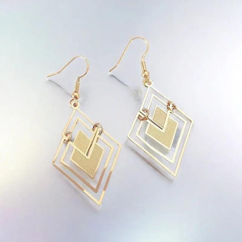 Gold rhombus hollow stud earrings with diamond shape on a light background