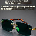 Dark green tinted frameless sunglasses with crystal lenses, shown with a hard protective case and cleaning cloth.