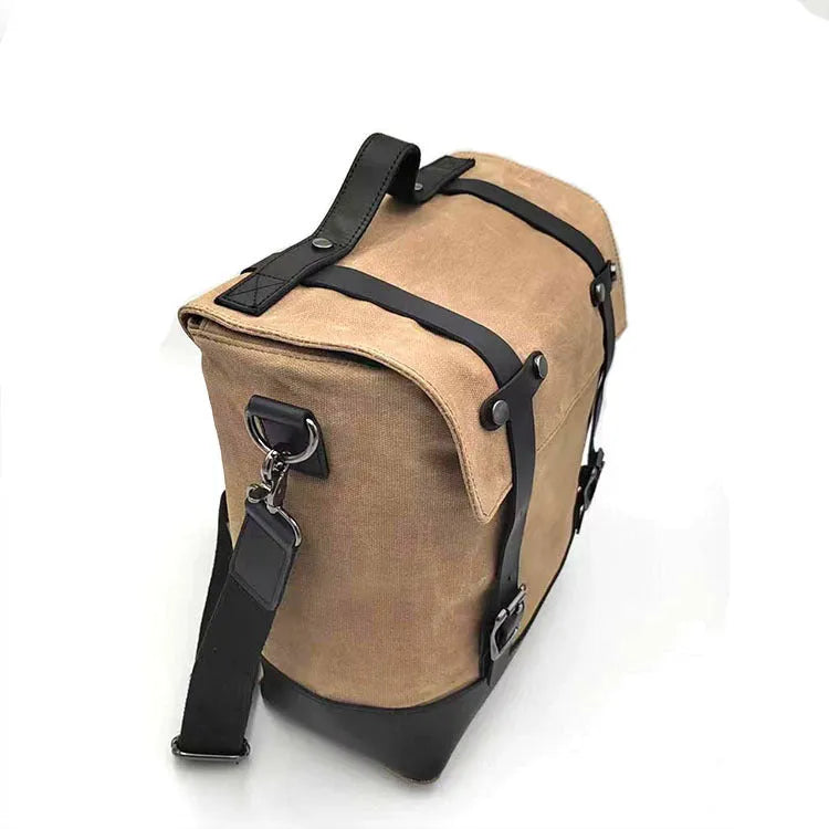 Black waterproof canvas motorcycle side bag with cowhide trim mounted on a bike