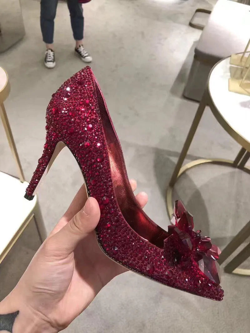 Gold women's pointed toe high heels with rhinestone and sequin decoration on a stiletto heel.