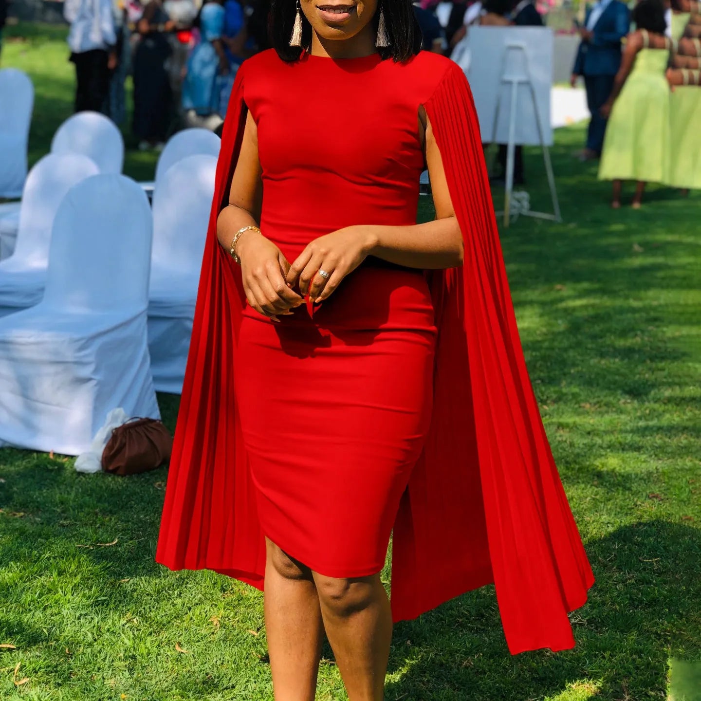 A woman wearing a long sleeve, high-waist pleated evening gown in a solid colour, showcasing the floor-length skirt and round neckline.