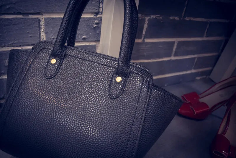 Women's PU messenger bag in black with zipper pocket and shoulder strap, top view with mini iPad inside.