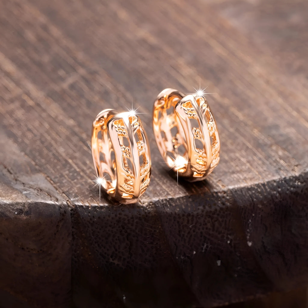 Rose gold coloured copper earrings with a hollowed-out leaf design on a heart shape.