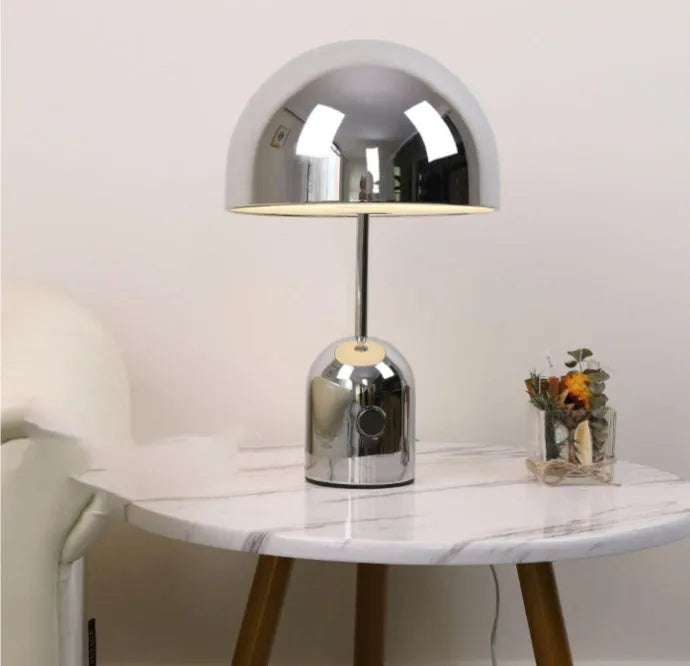 Mushroom-shaped table lamp with metal base in rose gold finish on wooden surface