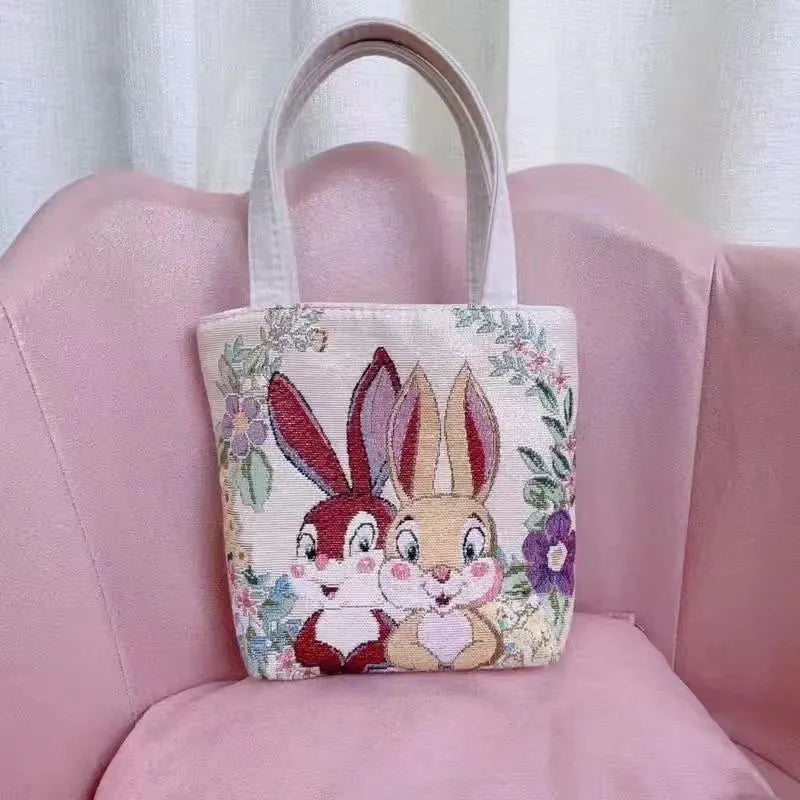 Double-sided embroidered canvas tote bag with gold wire trim, shown in a selection of seven colourways.