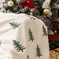 White polyester Christmas plush sofa blanket with embroidered Christmas tree design on a sofa