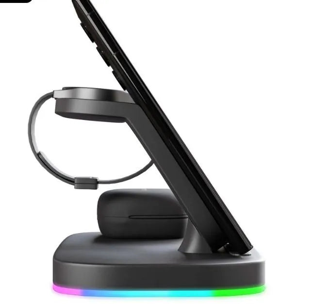 A vertical 3-in-1 wireless charging stand holding a mobile phone, a smartwatch, and headphones on a desk.