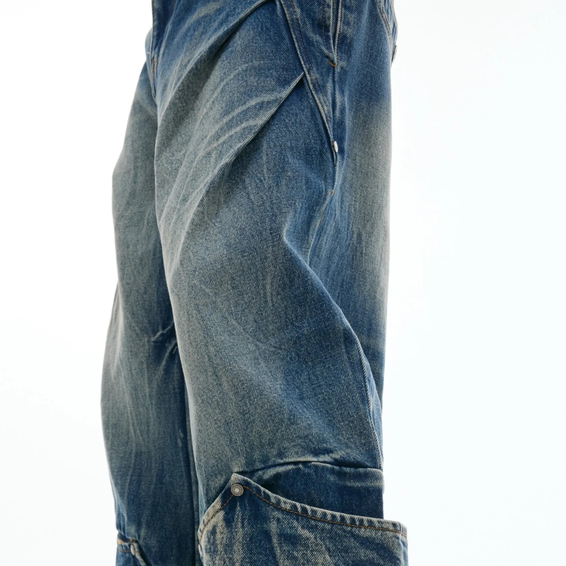 Man wearing verdant blue loose-fit retro jeans with a distinctive white burst pattern wash and a curved knife leg cut.