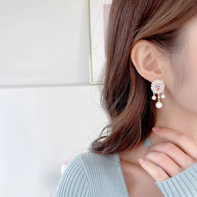 Pair of oval copper earrings with inlaid zircon and a white pearl tassel drop.