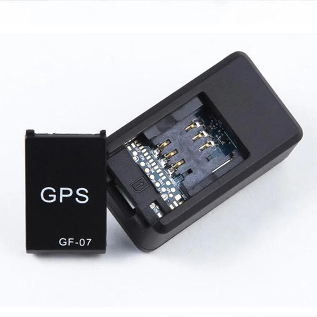 Small black magnetic GPS tracker device next to a micro-USB cable on a table.