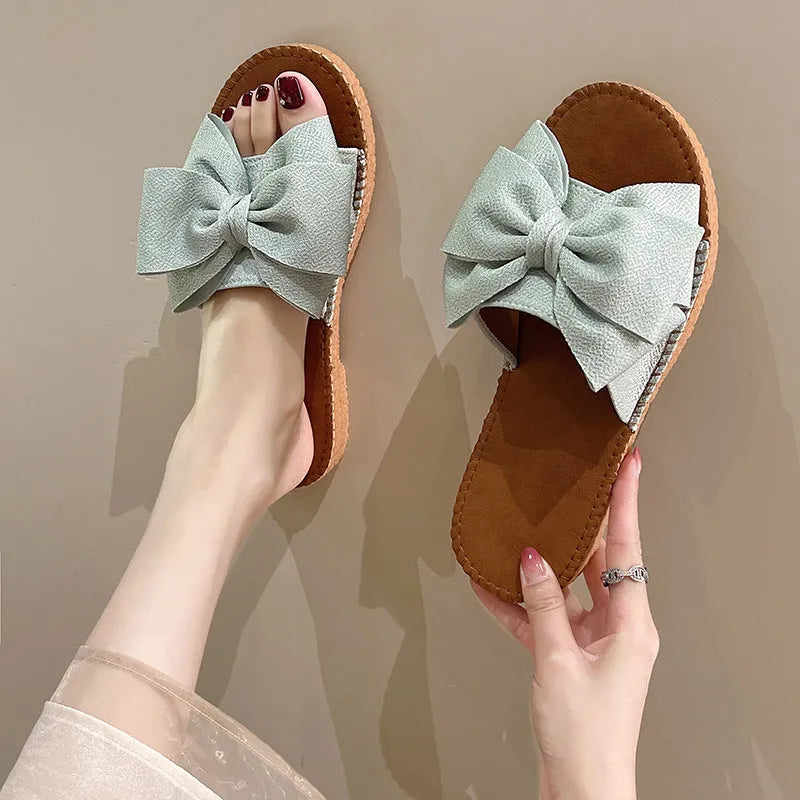 Women's slip-on suede sandals with bow detail in beige, light green, and pink colour options