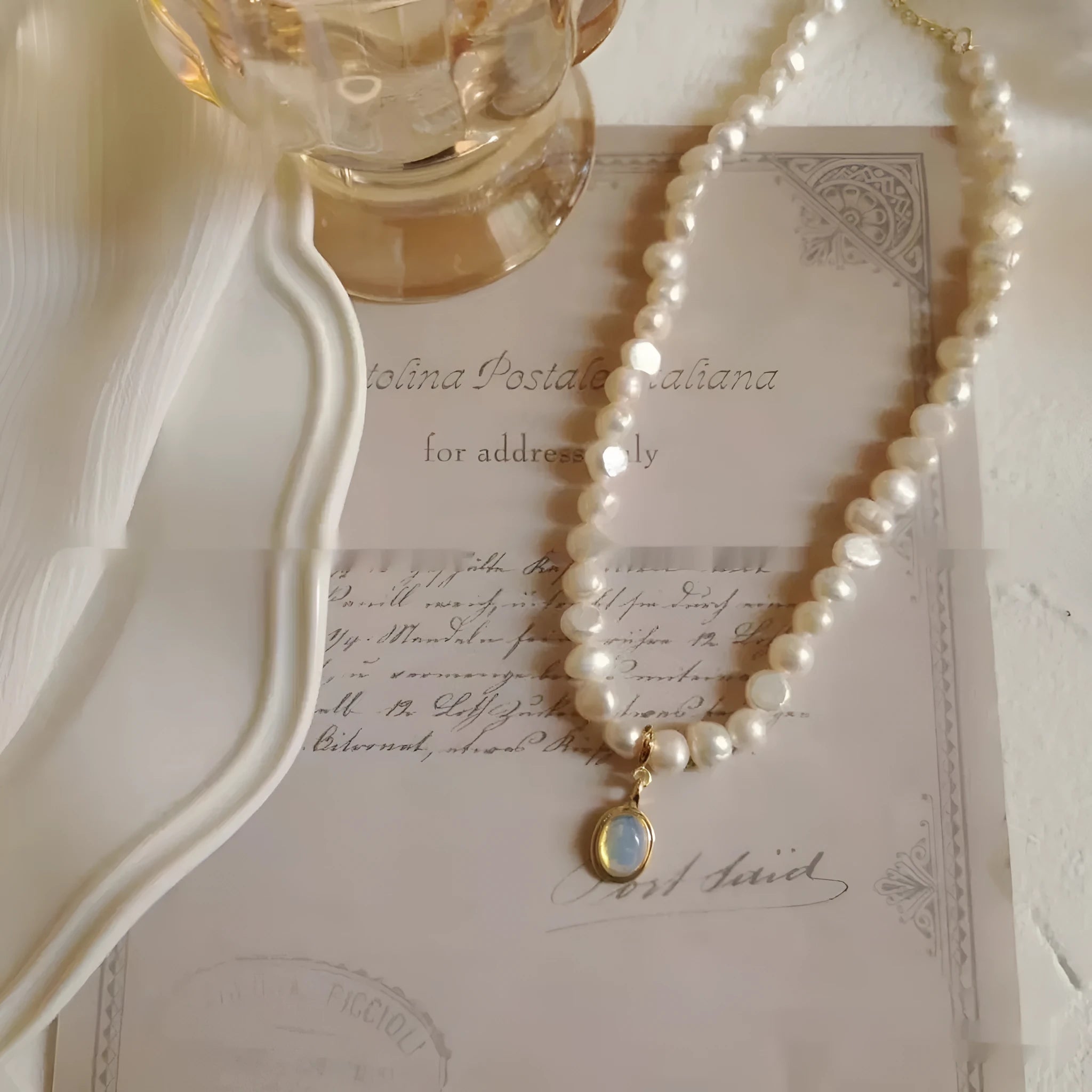 Gold electroplated adjustable vintage pearl necklace with a geometric charm on a black background.