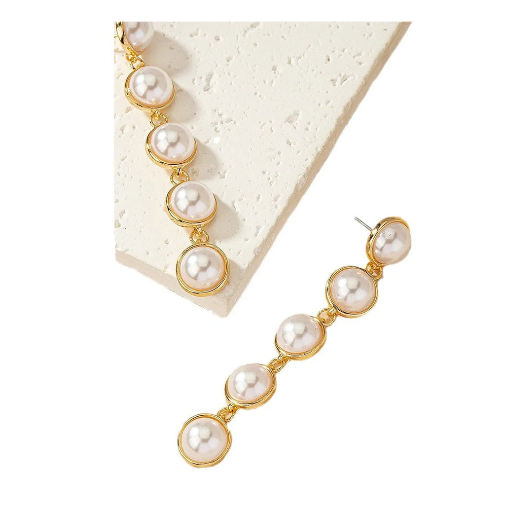 White long pearl tassel drop earrings made of electroplated metal with water flow design on white background
