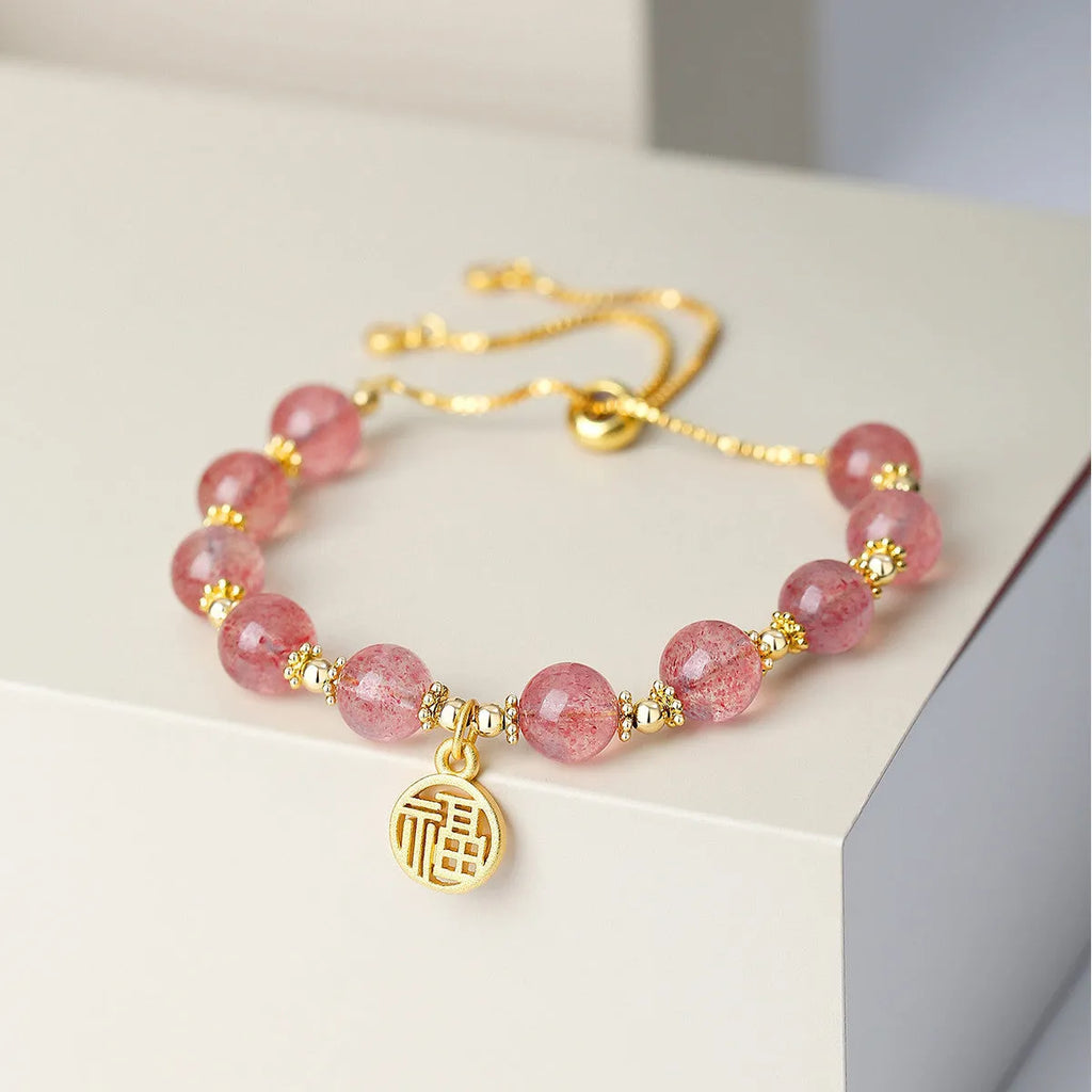 Women's strawberry quartz bracelet with geometric charms and fu character on wrist
