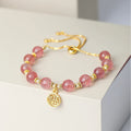 Women's strawberry quartz bracelet with geometric charms and fu character on wrist