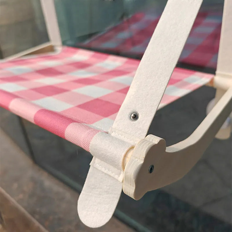 Green wooden cat window hammock with suction cups attached to glass, showing a removable linen mat.