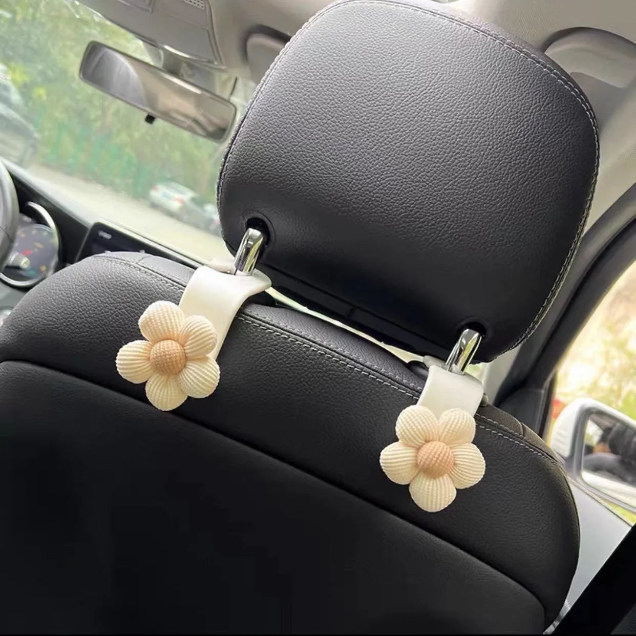 Khaki-coloured plastic car seat hook with a small decorative flower for storage.