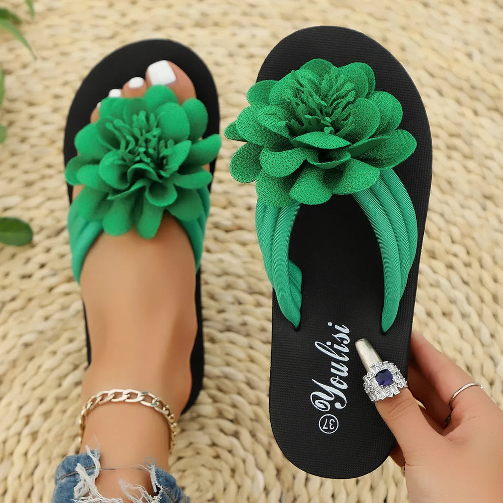 A pair of casual beige flip-flops with a floral decoration on the strap and a lightweight EVA sole.