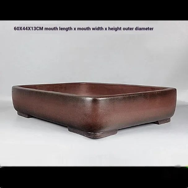 Large rectangular handmade antique purple clay flower pot on a table.