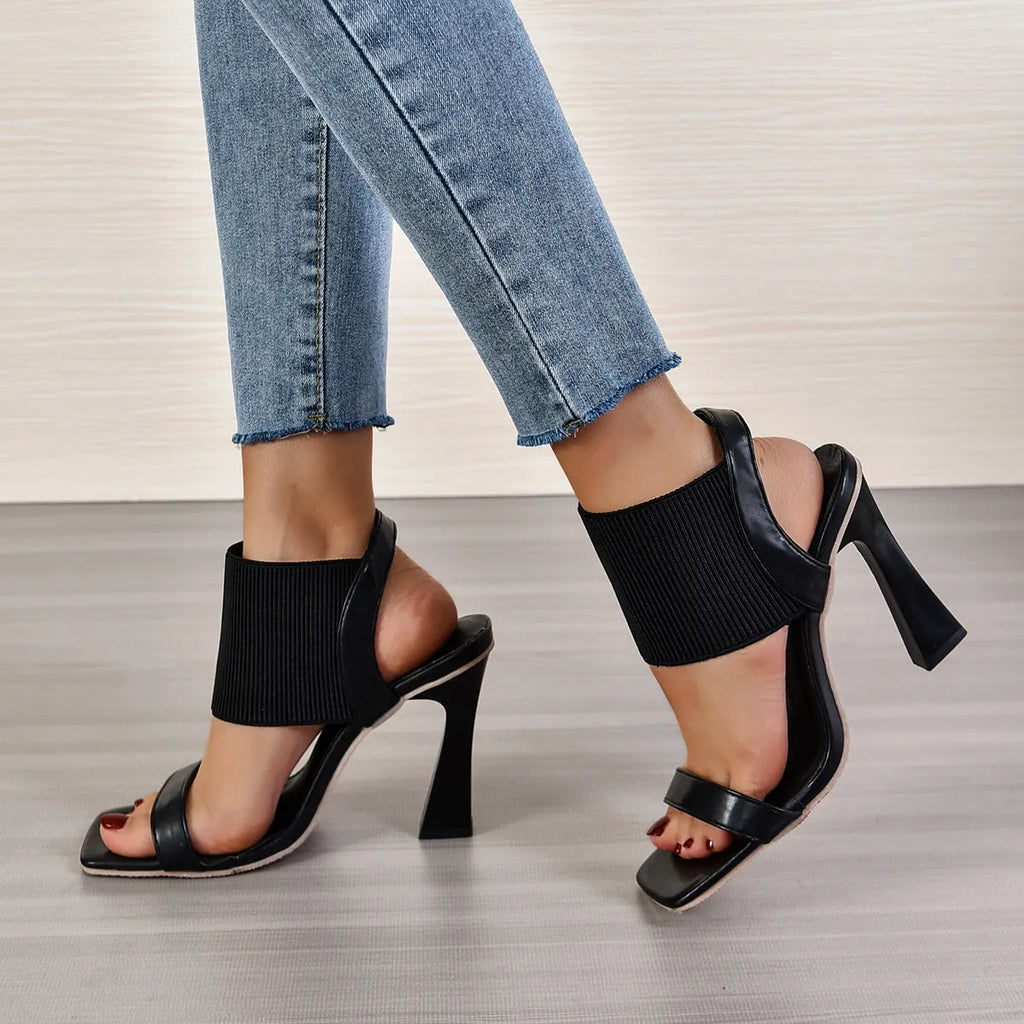 Women's black high heel sandals with an elastic strap across the foot and a rubber sole