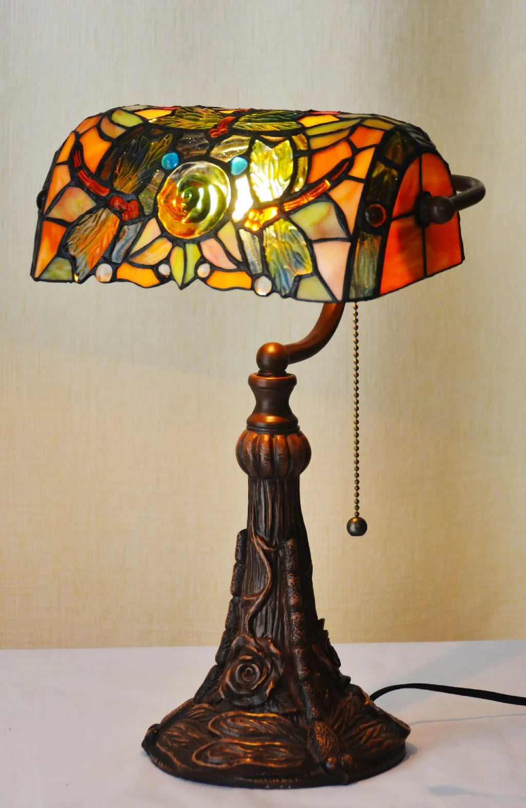 Tiffany-style table lamp with colourful stained glass shade and resin base on a desk