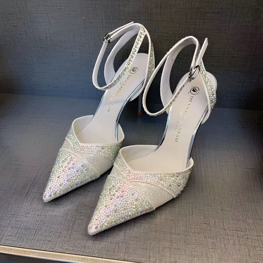 Women's black hollow high heel shoe with red sole and pointed toe, shown next to a silver pair.