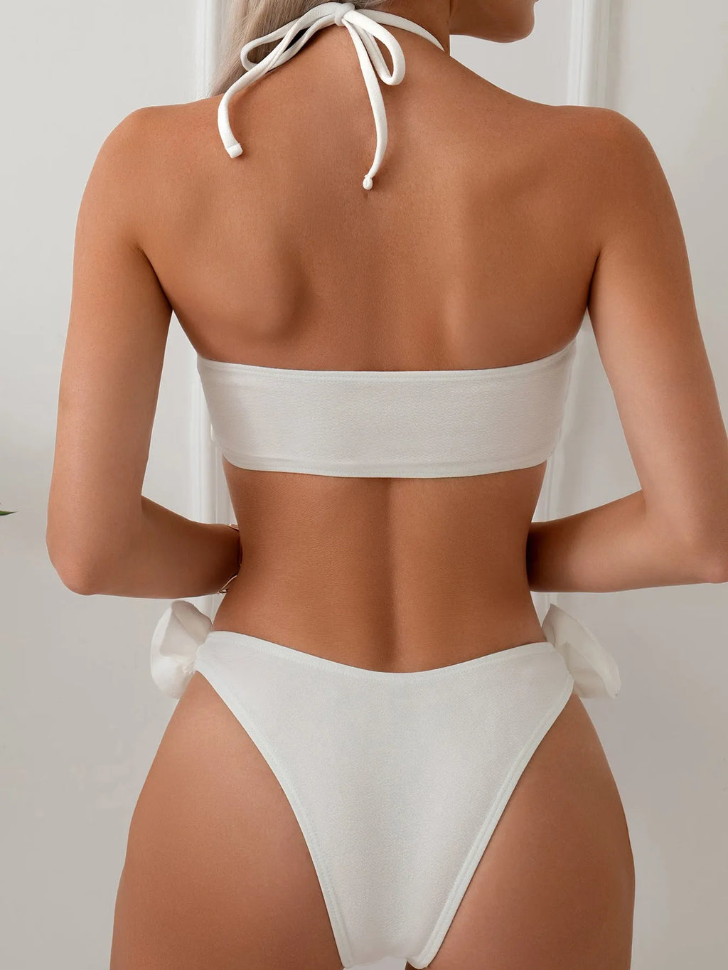 White women's swimsuit with 3D floral pattern, halter neck, and lace-up back.