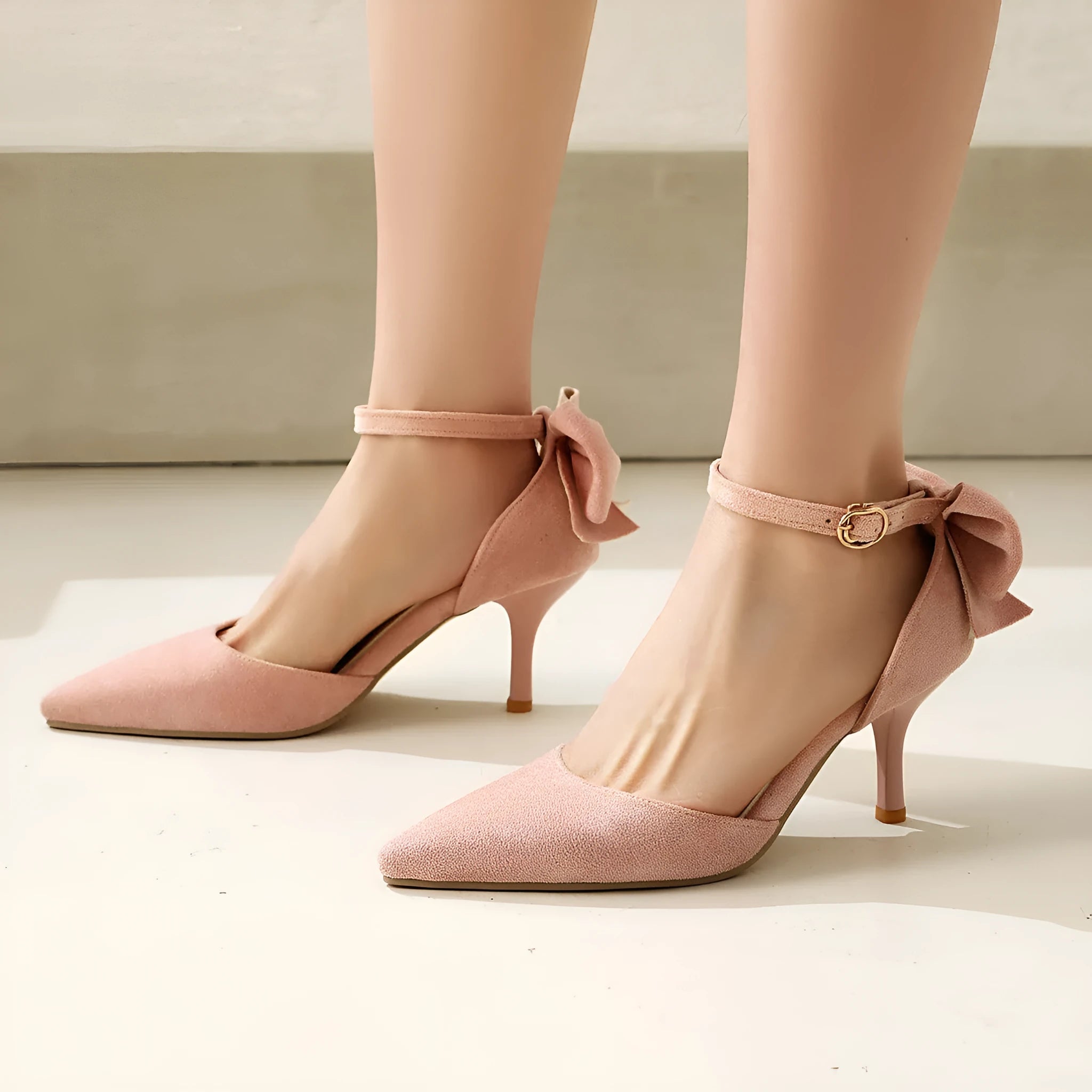 Women's black suede stiletto high heels with pointed toe and decorative bowknot.