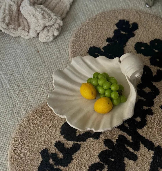 White resin fruit plate ornament shaped like a shell on a table