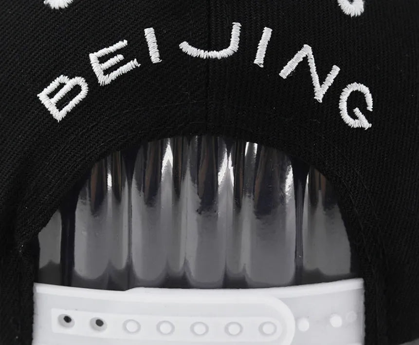 Black cotton baseball cap with white embroidered lettering on the front, showing adjustable back strap.