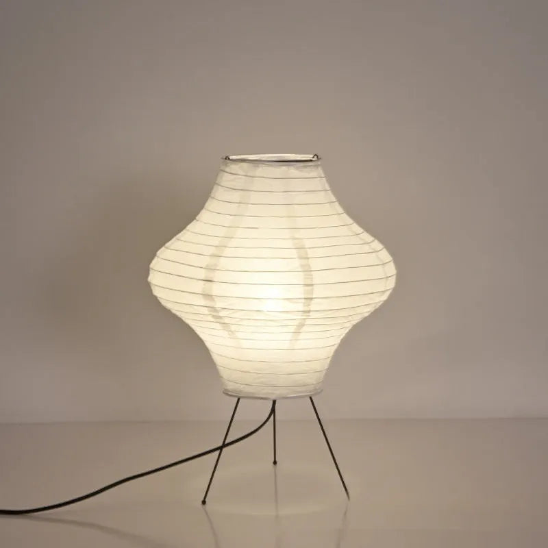 Japanese style table lamp with a white paper shade and a wooden base on a table.