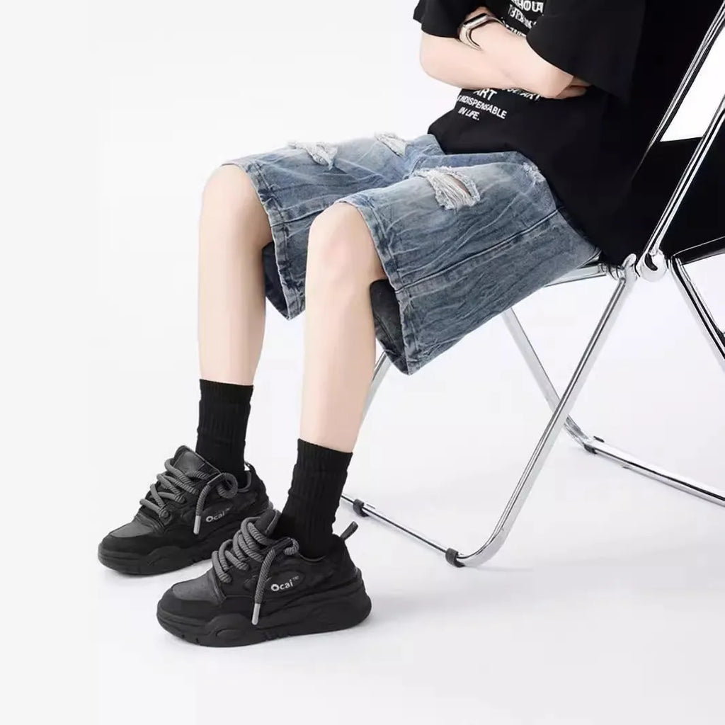 Men's washed denim shorts with ripped detailing in black or blue, showing loose retro style and fifth-pants length