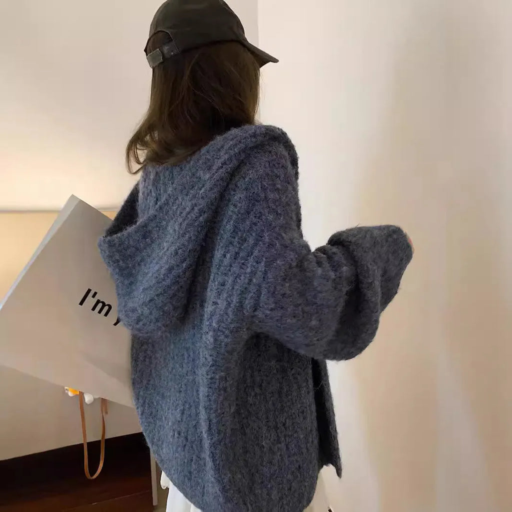 Woman wearing a thick dark grey hooded zip-up cardigan, loose fit.