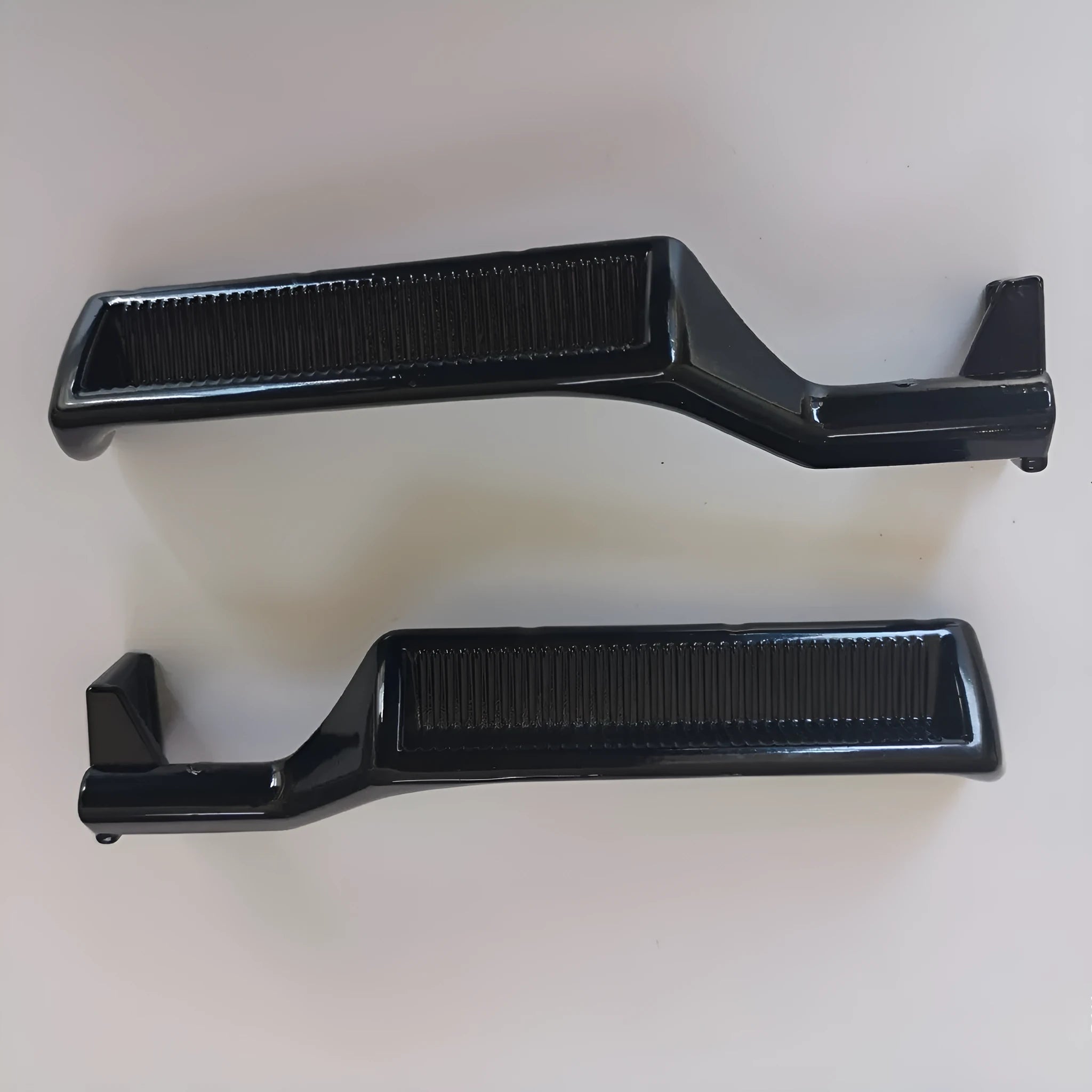 Pair of black zinc alloy automobile interior door handles, one left-hand and one right-hand.