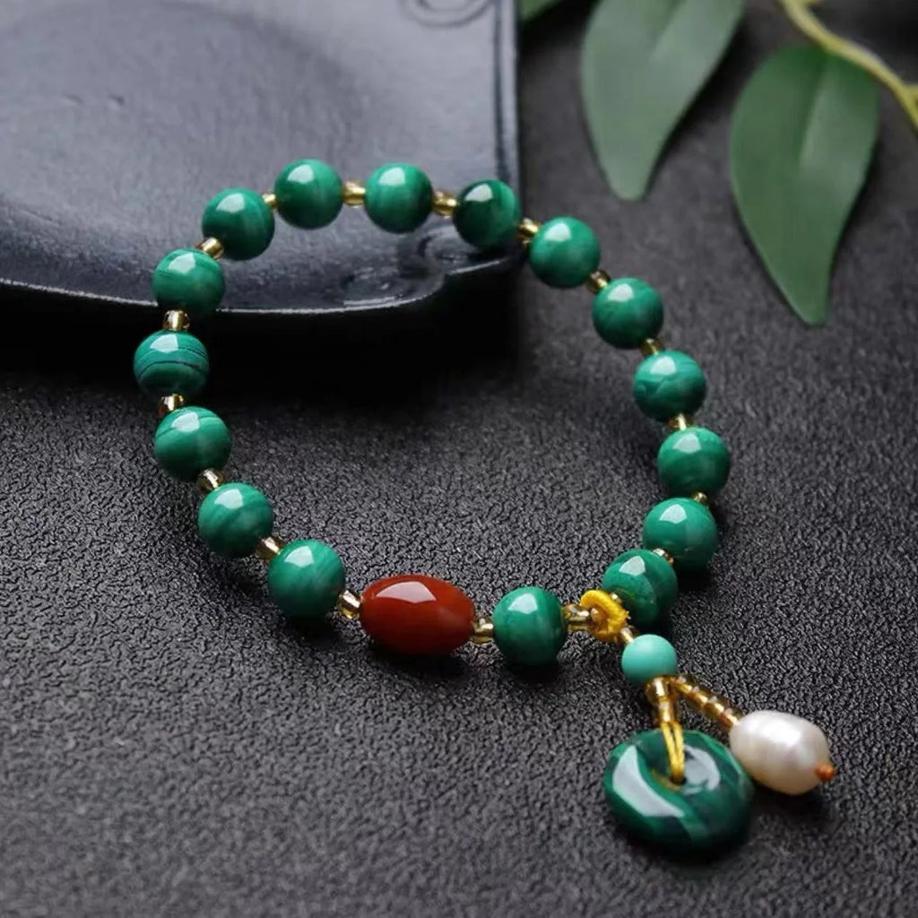Close-up of a natural malachite and red agate bracelet with 7-8mm barrel beads on a wrist.