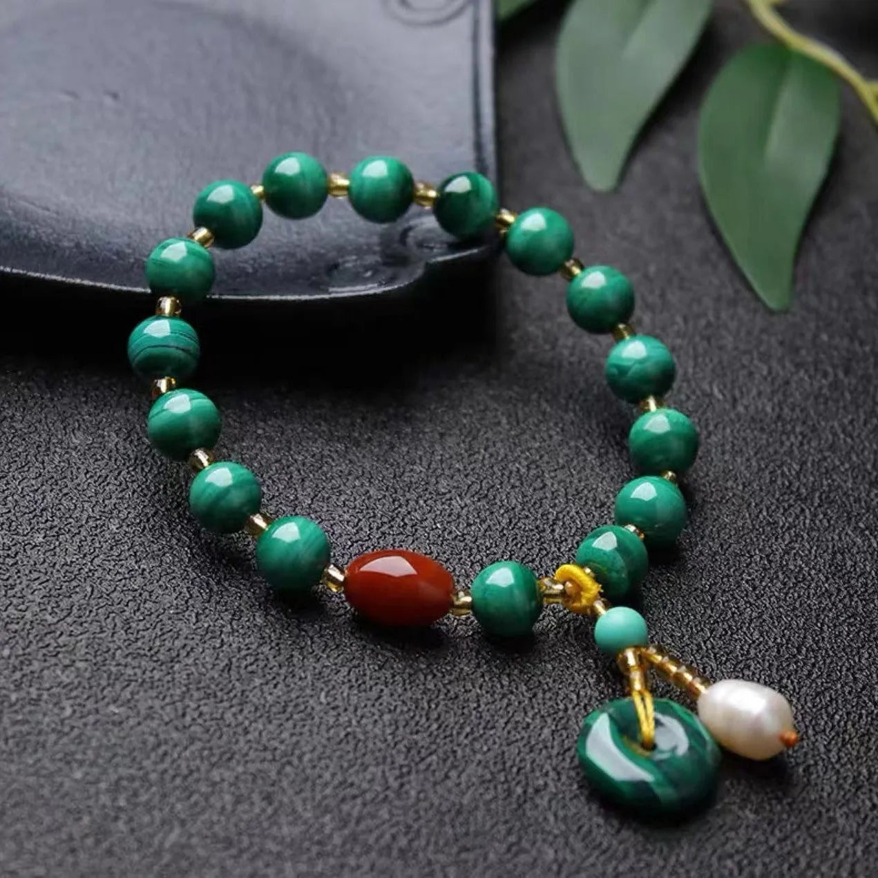 Close-up of a natural malachite and red agate bracelet with 7-8mm barrel beads on a wrist.