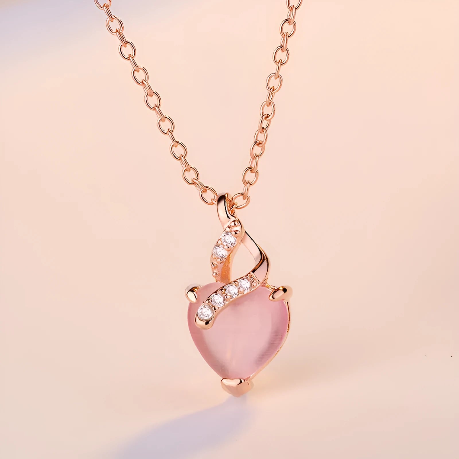Women's pink heart crystal pendant necklace with rose gold chain on white background