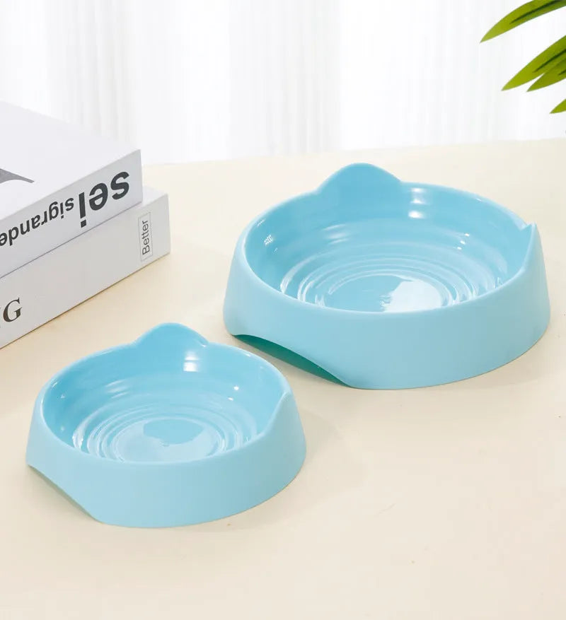 Blue ceramic dog slow feeder bowl with internal maze design, shown next to a green and pink version.