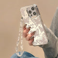 Transparent iPhone case with a built-in round mirror and a painted pink bow decoration on the back.