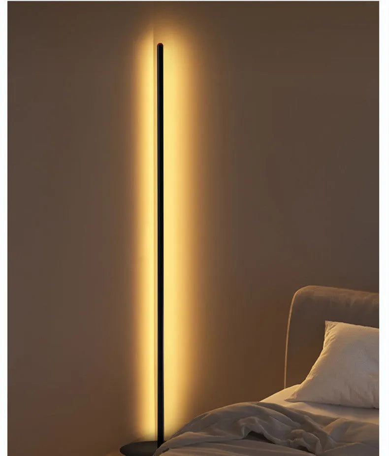 Slender vertical aluminium alloy LED floor lamp in a modern design next to a sofa.