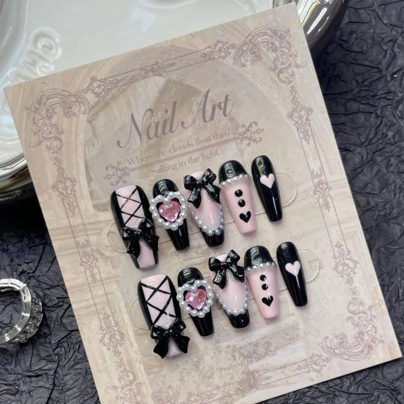Hand-painted black and pink heart design on detachable plastic manicure nails in cat's eye style.