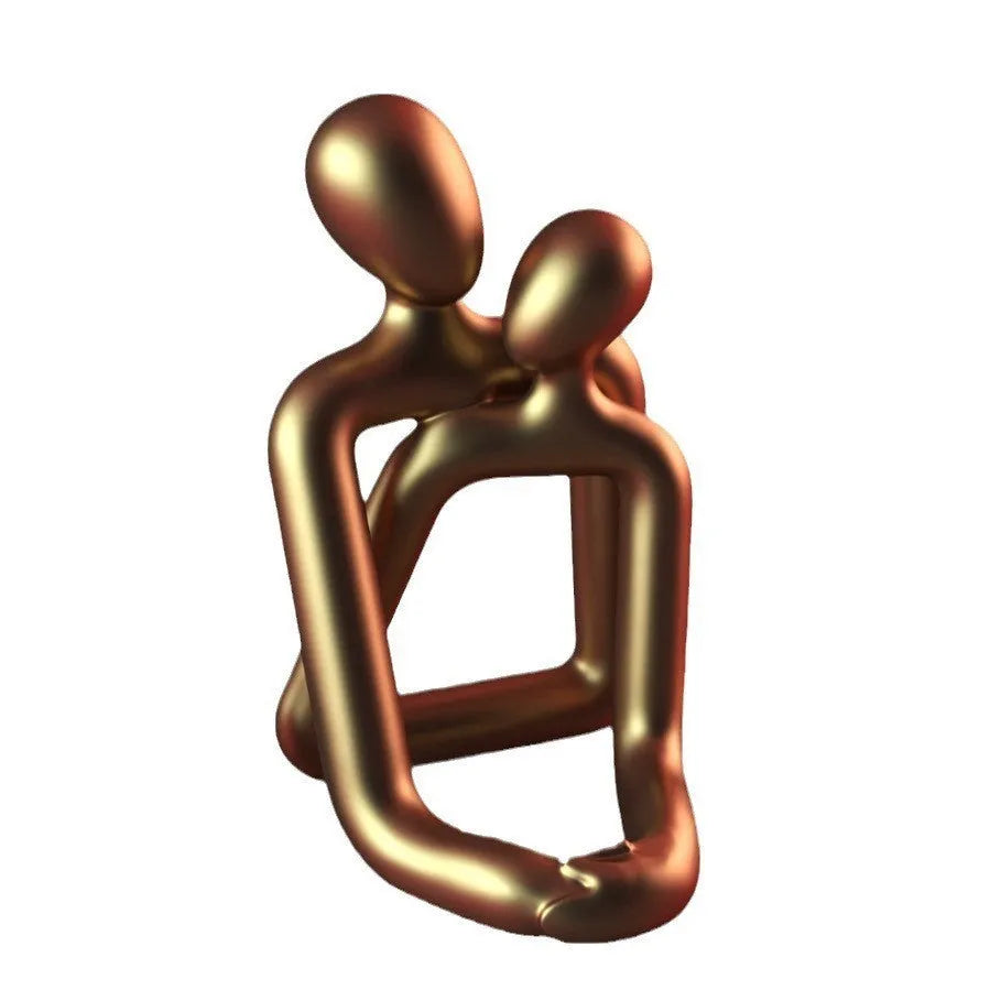 Modern loving couple resin statue in milky white or gold colour on a wooden desk.