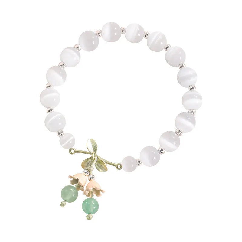 Close-up of a women's opal cat's eye stone beaded bracelet with diamond-shaped beads on a wrist.